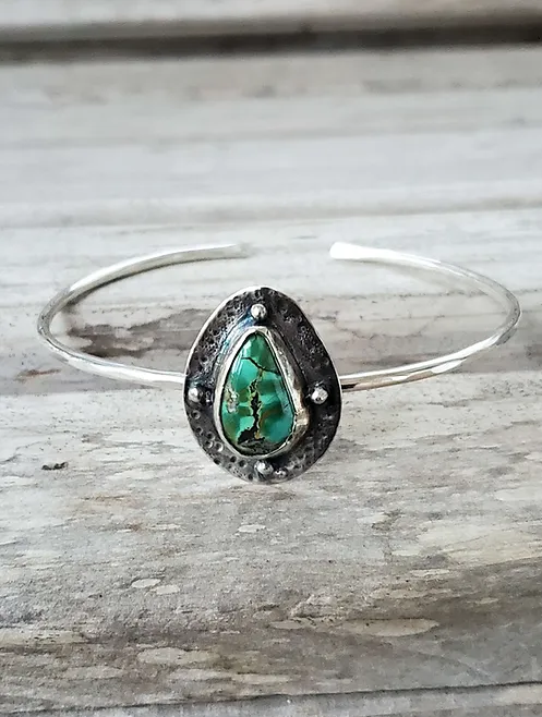 Teardrop Turquoise set in darkened sterling silver on a slim sterling silver bangle bracelet set in bezel with 4 round balls embedded in the bezel