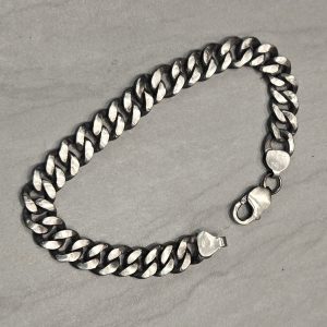 Cuban Link Sterling Silver Chain Bracelet with lobster clasp opened on a gray surface