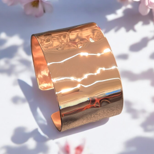 Wide Polished Hammered Copper Cuff Bracelet shown on a white background with spring flowers