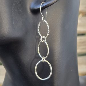 Varying Textured Slim Oval Dangle Sterling Silver French Wire Earrings shown on a mannequin
