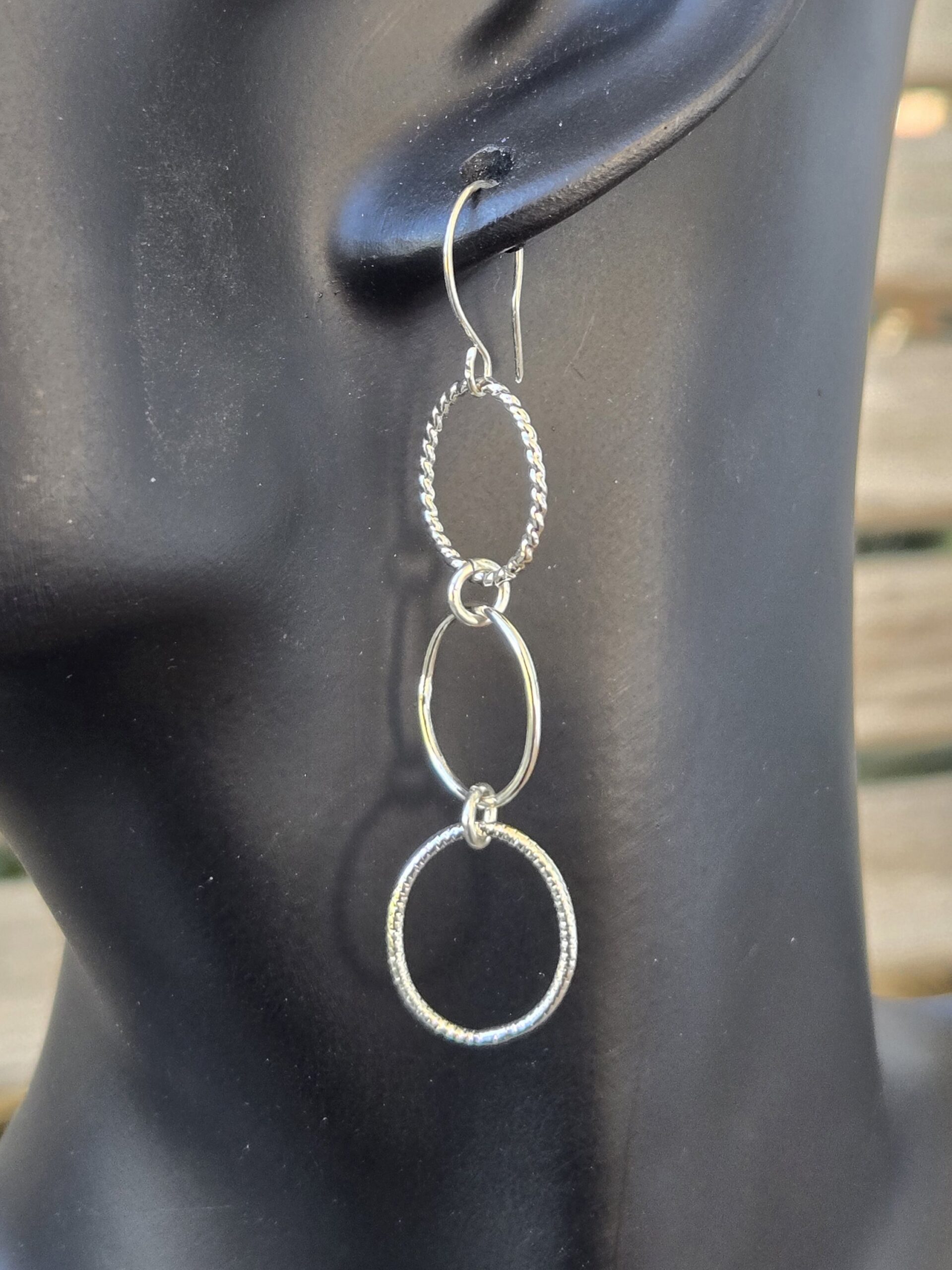 Varying Textured Slim Oval Dangle Sterling Silver French Wire Earrings shown on a mannequin
