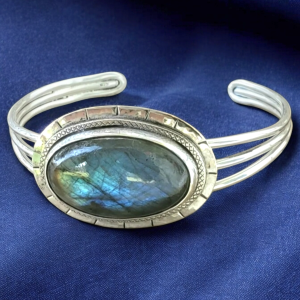 Oval Labradorite Cabochon in a sterling bezel with textured edging set on a three stranded bracelet