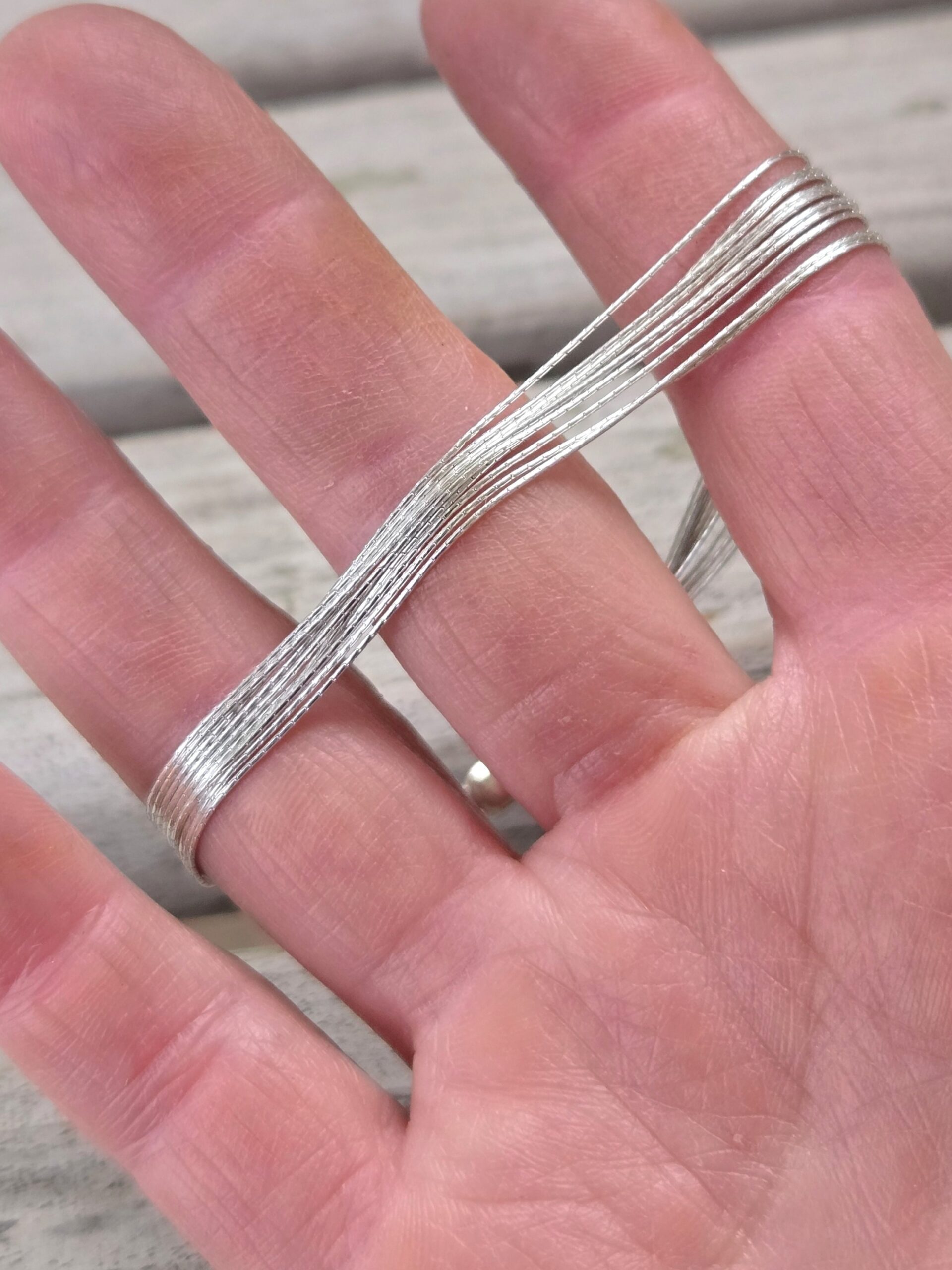 Finely Stranded Sterling Silver Bracelet with Lobster Clasp in model's hand showing the strands flow independently