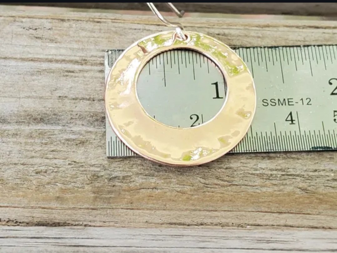 Hammered copper circles with circular center cutout on sterling silver french wire shown on ruler to indicate they are roughly 1 1/4" wide